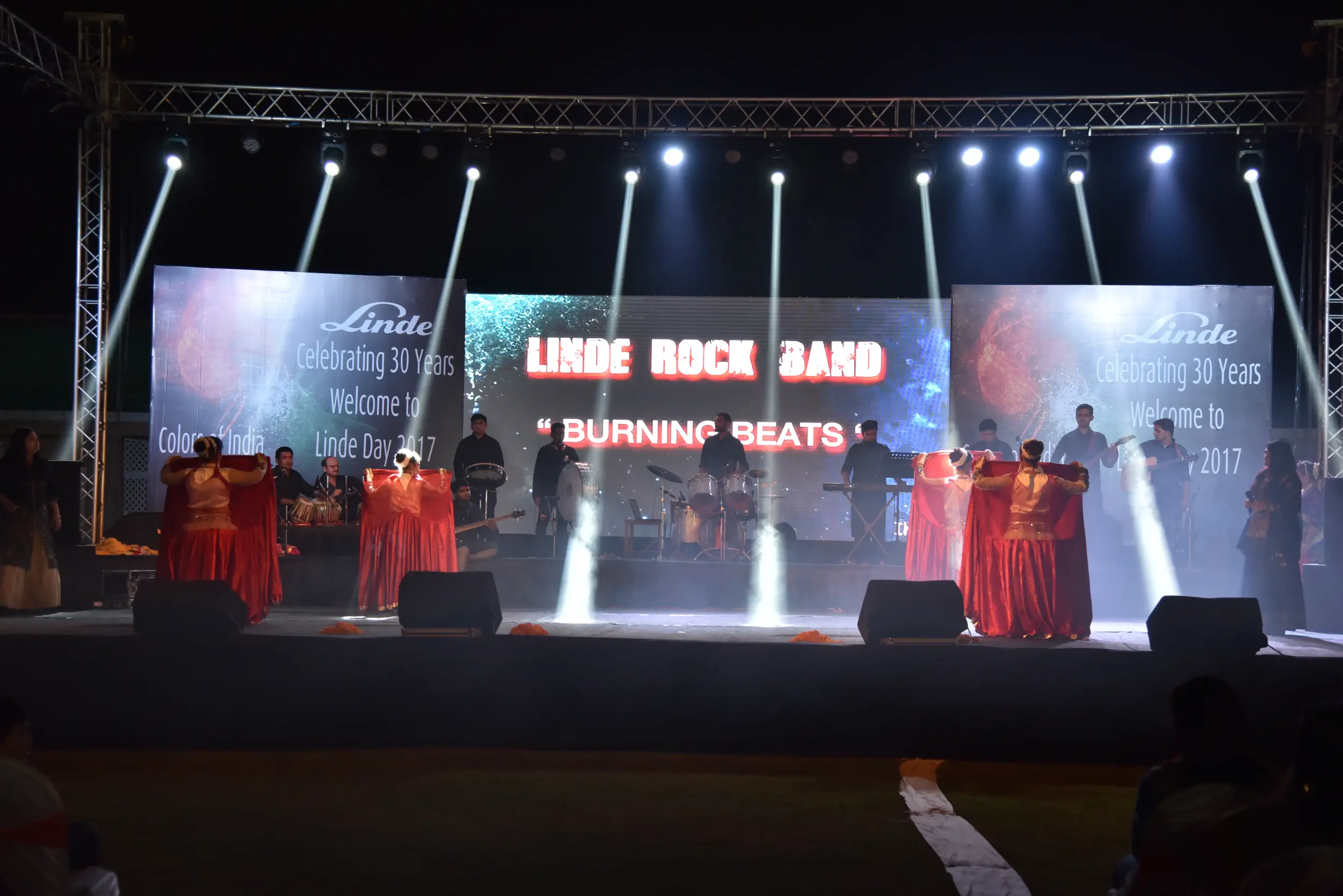 Man and woman speaking on stage at night with blue lighting